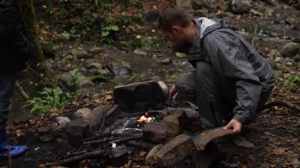 4K, câmara lenta. um homem-turista atira um fogo para uma grade na floresta . — Vídeo de Stock