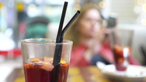 Hermosa mujer está descansando en un café, beber vino caliente caliente con especias y mirando en su teléfono inteligente. 4k, desenfoque de fondo . — Vídeos de Stock