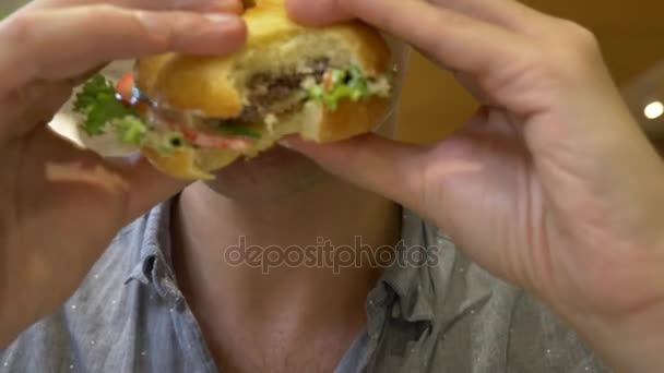 Mann isst einen Hamburger. Nahaufnahme. Schnitzelsandwich. 4k — Stockvideo