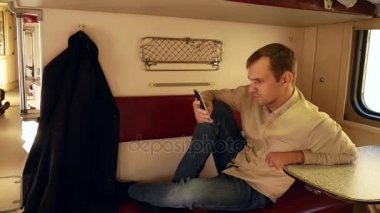 Bir kişi bir smartphone bir yolcu treni bir kompartımanda kullanır. 4k