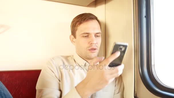 Uma pessoa usa um smartphone em um compartimento de um trem de passageiros. 4k — Vídeo de Stock