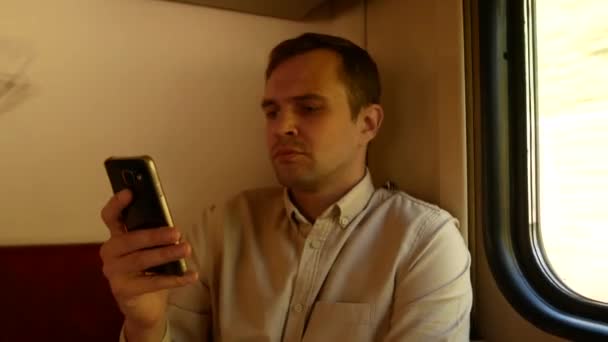 Una persona utiliza un teléfono inteligente en un compartimento de un tren de pasajeros. 4k — Vídeos de Stock