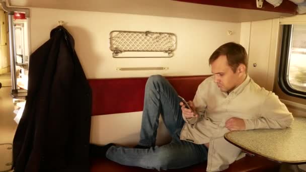 Uma pessoa usa um smartphone em um compartimento de um trem de passageiros. 4k — Vídeo de Stock