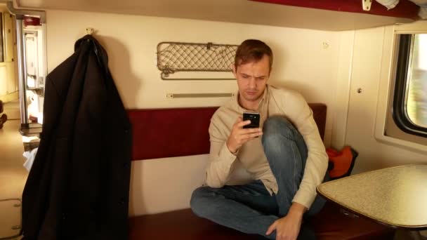 Bir kişi bir smartphone bir yolcu treni bir kompartımanda kullanır. 4k — Stok video