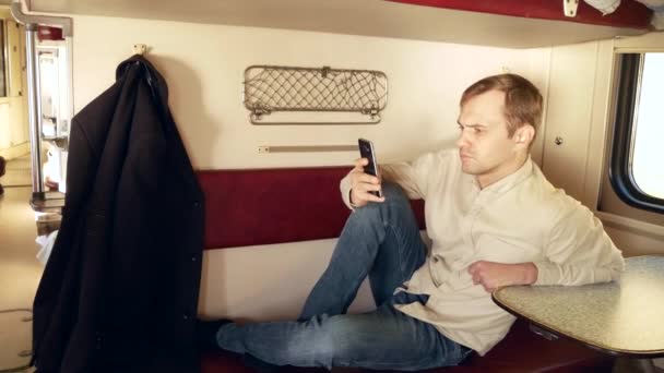 Una persona utilizza uno smartphone in un compartimento di un treno passeggeri. 4k — Video Stock