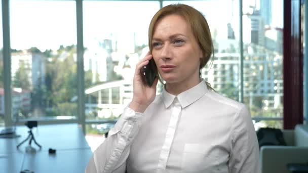 Femme d'affaires dans un bureau moderne avec une fenêtre panoramique, journée ensoleillée, ordinateur portable, tablette, utiliser un téléphone mobile dans une situation. 4k, au ralenti — Video