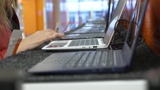 Mulher seleciona um laptop em uma loja de eletrônicos. 4k, câmera lenta — Vídeo de Stock
