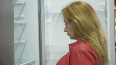 Bir kadın bir ev aletleri mağaza, 4 k, ağır çekim bir buzdolabı satın alır.