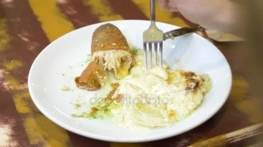 bir kadın bir restoranda bir tavuk rulo patates ile yemek. 4k