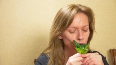 Güzel sarışın kadın bir yaprak ıspanak yemek. Bir kadın bir yeşil taze sebze ağzına koyar. Bir vejetaryen veya sağlıklı gıda kavramı. 4k, ağır çekim