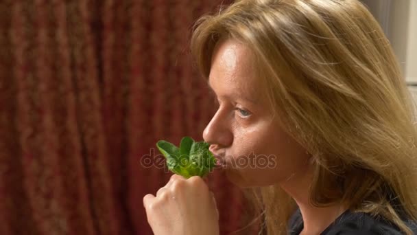 Mooie blonde vrouw een blad van spinazie eten. Een vrouw zet een groene verse groente in haar mond. Het concept van een vegetarische of gezonde voeding. 4k, slow-motion — Stockvideo