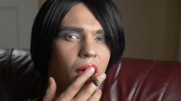 Mladý muž v obraze transsexuál svůdně kouřil doutník v soumraku a uvolnění kouř do kamery. 4k, pomalý pohyb — Stock video