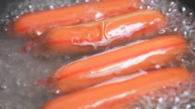 çiğ sosis bir gaz sobası üzerinde suda haşlanmış. 4k, ağır çekim
