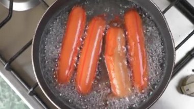 çiğ sosis bir gaz sobası üzerinde suda haşlanmış. 4k, ağır çekim