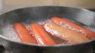 çiğ sosis bir gaz sobası üzerinde suda haşlanmış. 4k, ağır çekim