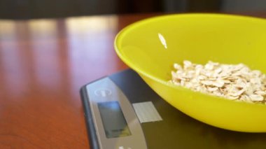 biri yulaf ezmesi, mutfakta elektronik bir ölçekte bir parça ölçer. Kıç platformu ağırlığında bir daire üzerinde duran bir derin yuvarlak kaseye dökün. 4k, ağır çekim, dolly atış