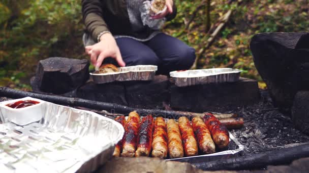 4k, au ralenti. le touriste cuisine des saucisses sur un mini grill dans la forêt. gros plan — Video