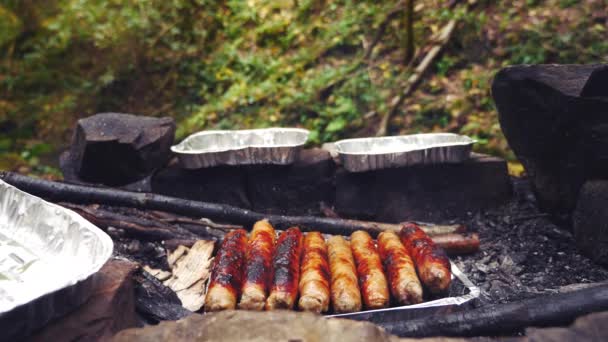 4k, au ralenti. le touriste cuisine des saucisses sur un mini grill dans la forêt. gros plan — Video