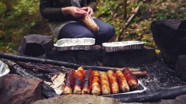 4k, au ralenti. le touriste cuisine des saucisses sur un mini grill dans la forêt. gros plan — Video