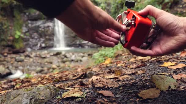 4k, rallenta. il turista accende il bruciatore a gas ai piedi della montagna, contro la cascata . — Video Stock