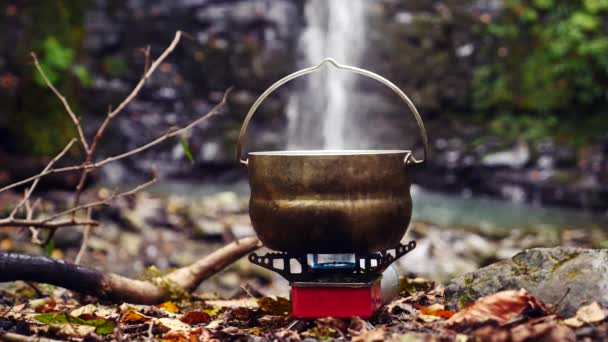 4k, slow motion. tourist bowler on a burner at the foot of the mountain, against a waterfall — Stock Video