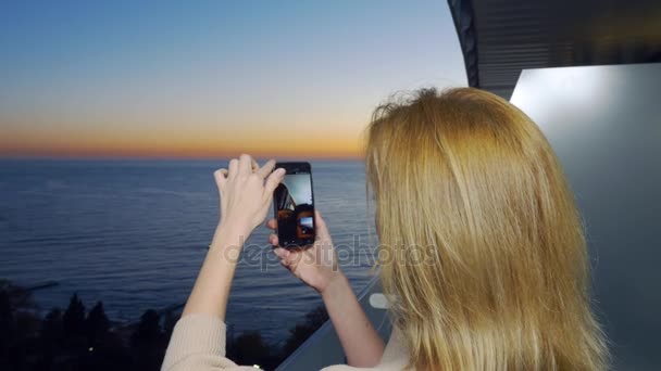 Çekici bir genç kadın, bir smartphone kullanarak balkon resort adlı bir kadın tarafından bir uygulama akıllı cep telefonu kullanarak video iletişimi iletişim kurar. 4k — Stok video