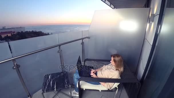 4k. жінка працює на ноутбуці на балконі курортного готелю з видом на море. Віддалена робота будь-де . — стокове відео