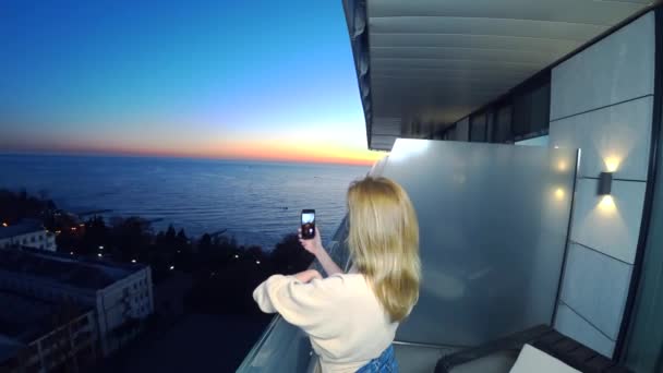 Een aantrekkelijke jonge vrouw met behulp van een smartphone in het balkon resort, communiceert een vrouw door video communicatie toe gebruikmakend van een toepassing op een slimme telefoon van de cel. 4k — Stockvideo