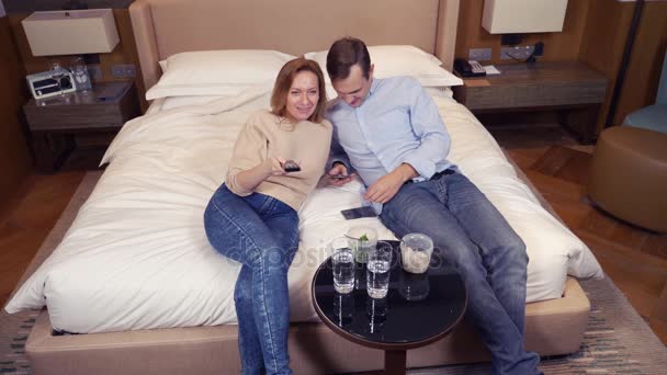 Um casal de homens e mulheres, vegetarianos, sentados à noite na cama, assistindo TV e comendo brócolis. 4k — Vídeo de Stock