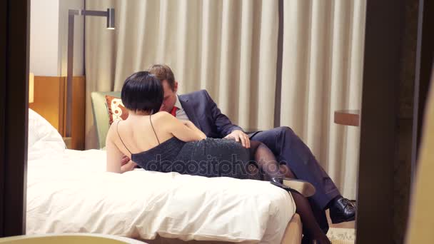 Casal, homem de negócios e mulher morena com cabelo curto beber álcool na cama no quarto de hotel. 4k — Vídeo de Stock