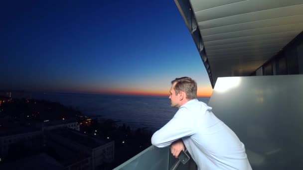 An attractive young man using a smartphone on the balcony of a spa hotel. 4k close-up — Stock Video