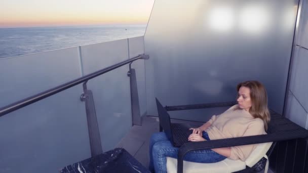 4k. femme travaillant sur un ordinateur portable sur le balcon d'un hôtel de villégiature avec vue sur la mer. Travail à distance partout . — Video