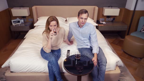 Hermosa pareja enamorada viendo televisión y bebiendo en un hotel. 4k — Vídeos de Stock