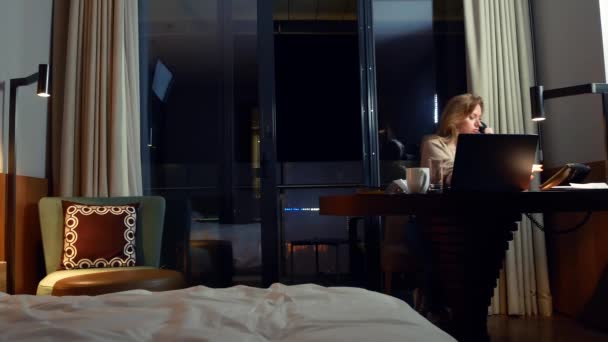 Bir masada bir dizüstü bilgisayarda bir otel odasında geceleri çalışan kadın. 4k. — Stok video