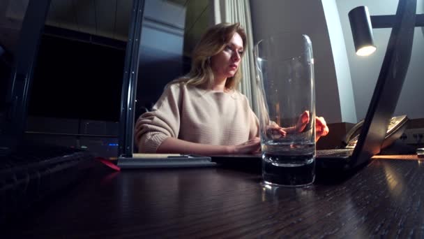 Kvinde, der arbejder på en bærbar computer ved et bord om natten på et hotelværelse. 4k . – Stock-video