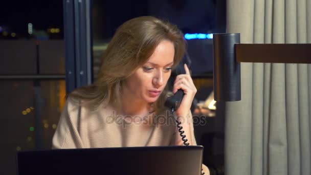 Mujer trabajando en un portátil en una mesa por la noche en una habitación de hotel. 4k . — Vídeos de Stock