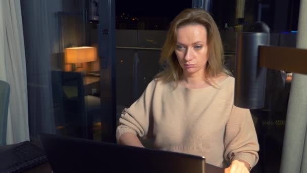 女性がホテルの部屋で夜のテーブルにラップトップに取り組んで。4 k. — ストック動画