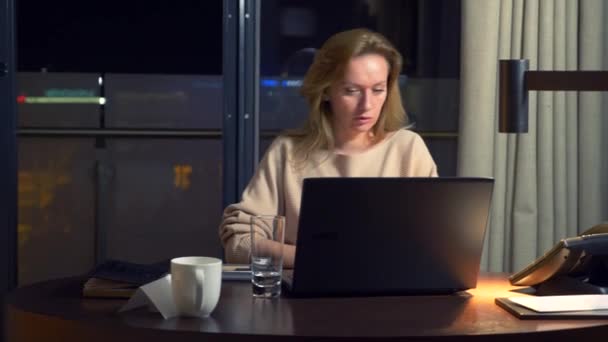A nő dolgozik egy laptop, egy asztalnál éjszaka egy szállodai szobában. 4k. — Stock videók
