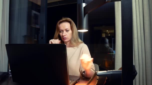 Frau arbeitet nachts an einem Laptop an einem Tisch in einem Hotelzimmer. 4k. — Stockvideo