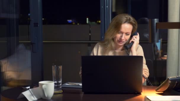 Mulher trabalhando em um laptop em uma mesa à noite em um quarto de hotel. 4k . — Vídeo de Stock