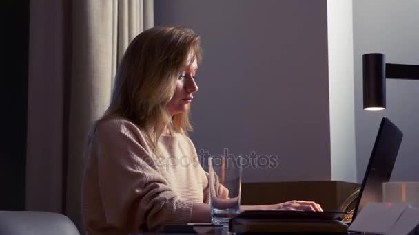 Frau arbeitet nachts an einem Laptop an einem Tisch in einem Hotelzimmer. 4k. — Stockvideo