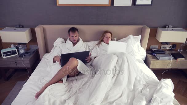 Young couple lying in bed using laptop computer, chatting online, girl and man in bedroom. Morning. 4k — Stock Video