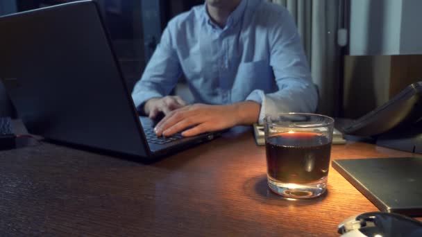 Hombre de negocios que bebe alcohol mientras trabaja con su computadora portátil en la noche, 4k — Vídeos de Stock