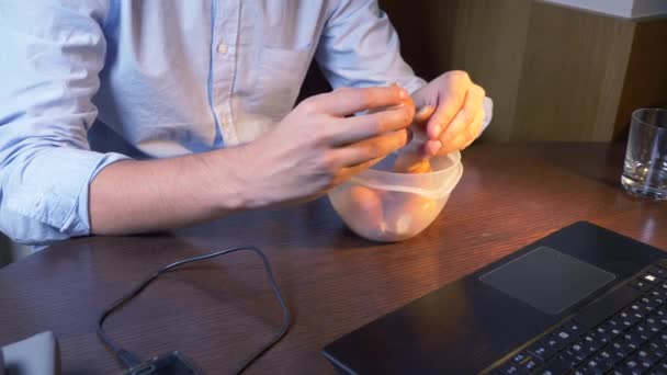 Egy ember eszik főtt csirke tojások élelmiszer konténer, működő-ra egy laptop, késő éjjel, egészséges ételek, a fehérje-diéta. 4k — Stock videók