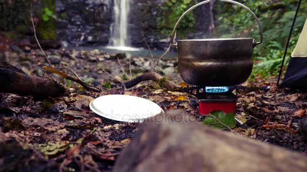 4k, Zeitlupe. Tourist Bowler auf einem Brenner am Fuße des Berges, gegen einen Wasserfall — Stockvideo