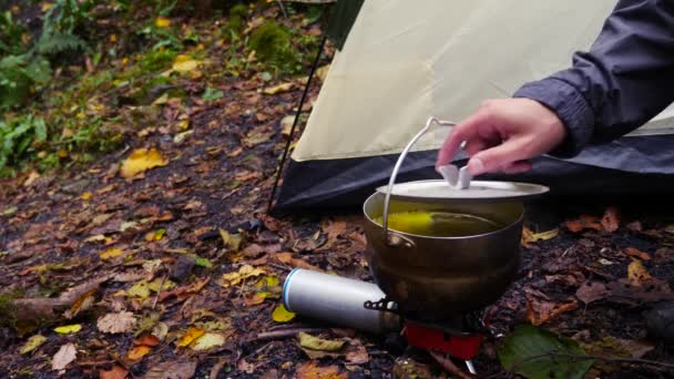 4k, slow-motion. toeristische bowler op een brander aan de voet van de berg, tegen een waterval — Stockvideo