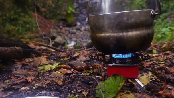 4k, Zeitlupe. Tourist Bowler auf einem Brenner am Fuße des Berges, gegen einen Wasserfall — Stockvideo