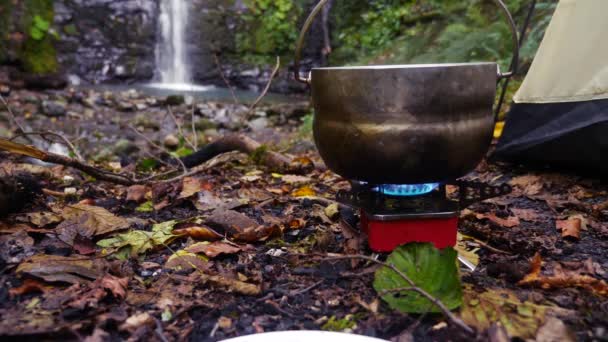 4k, gerakan lambat. pelempar wisata di kompor di kaki gunung, melawan air terjun — Stok Video