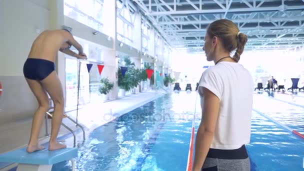 Entraînement d'athlète de natation. Le coach apprend au garçon à plonger dans la piscine sportive. 4k, au ralenti — Video