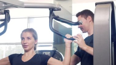 Genç Yetişkin kız onu kişisel antrenörü tarafından liderliğindeki simülatörleri bir egzersiz yapıyor. 4k, ağır çekim